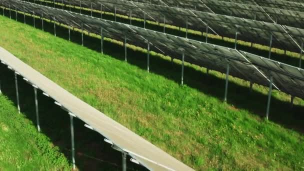 Çimenler üzerine inşa edilen güneş pilleri kırsal alanda yeşil enerji üretiyor. Güneşli bir günde elektrik santralinde fotovoltaik güneş panelleri - Video, Çekim