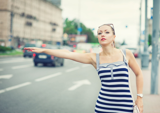 junge schöne Frau versucht, ein Taxi in der Stadt zu bejubeln - Foto, Bild