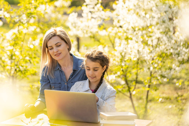 Anya segít a kislányának laptopot használni. A gyerek otthon tanul, házit csinál, vagy online tanul. Otthoni tanulás koncepciója - Fotó, kép
