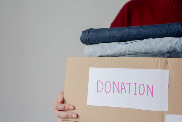 Woman holding a donate box with full of clothes - Foto, Imagen