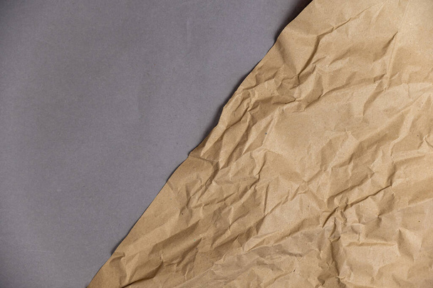 Kırışmış bir açık kahverengi kağıt yaprağı gri bir yüzey üzerinde yatar. Üst Manzara. Metin ve tasarım ögeleri için boşluk kopyala. - Fotoğraf, Görsel