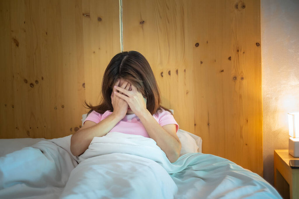 Frau, die Migräne hat, während sie zu Hause im Bett liegt. Schlaflosigkeit, Schlaflosigkeit, Müdigkeit, Leiden und Stress - Foto, Bild