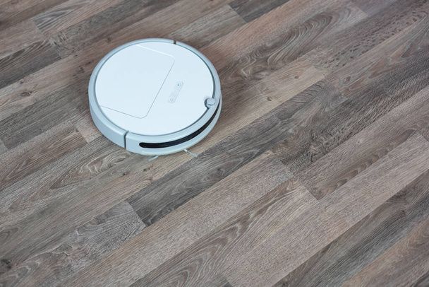 Hoovering floor with modern robotic vacuum cleaner indoors, closeup. - Photo, Image