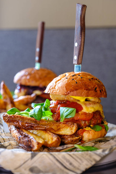 Két ízletes szaftos marhahús, sajt és zöldség burger az asztalon egy kávézóban. Nagy hamburger, amerikai gyorsétterem.. - Fotó, kép