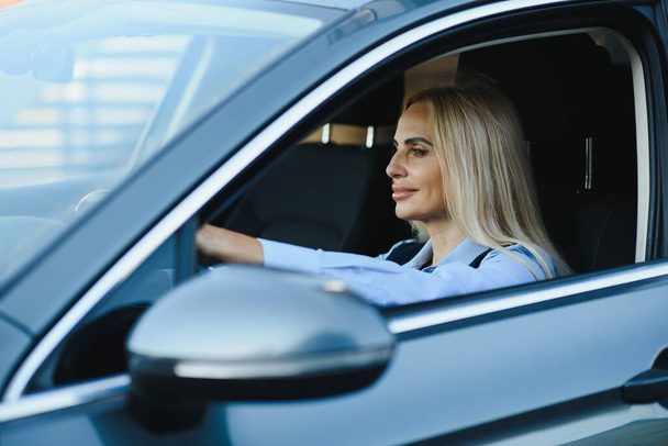 Businesswoman sitting in drivers seat in her car. - Fotoğraf, Görsel