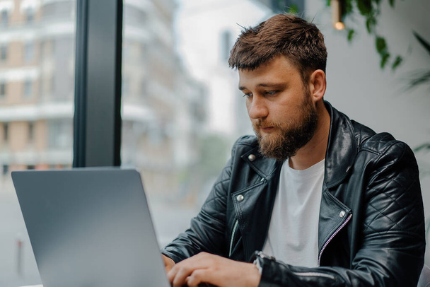 Jonge blanke zakenman zoomt in op laptop in café. College student met behulp van technologie, online onderwijs, freelance - Foto, afbeelding