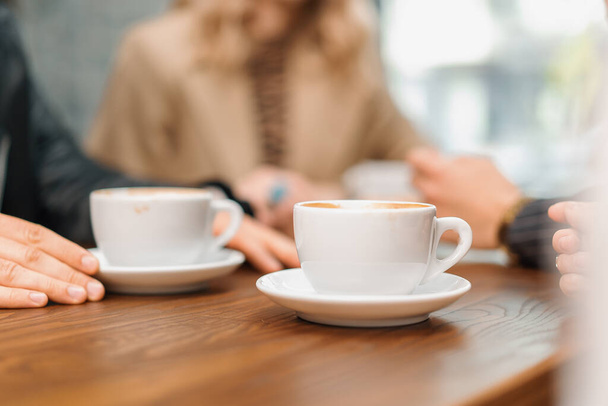Een kopje filterkoffie op een tafel in een coffeeshop, een luidruchtige groep vrienden - Foto, afbeelding