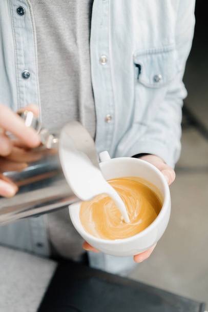 Barista fait du latte art dans un café de spécialité. Homme professionnel faisant couler le lait de ruisseau avec espresso - Photo, image