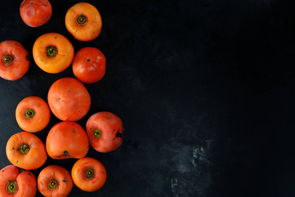 Fresh organic persimmons on black background  - Foto, immagini