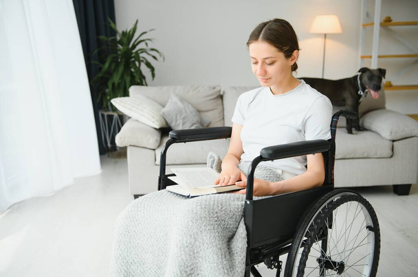 Young woman in wheelchair at home in living room - Valokuva, kuva
