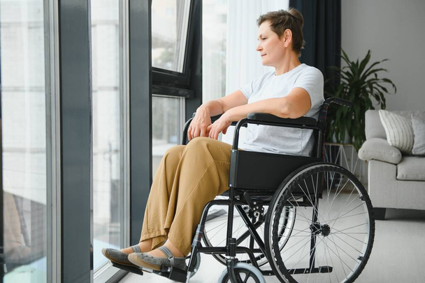 middle aged woman sitting on wheelchair. - Foto, imagen