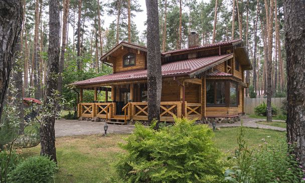 Maison en bois avec gazebo, pelouse et passerelle en béton dans la forêt. Maison en bois au bord du lac. Photo de haute qualité - Photo, image