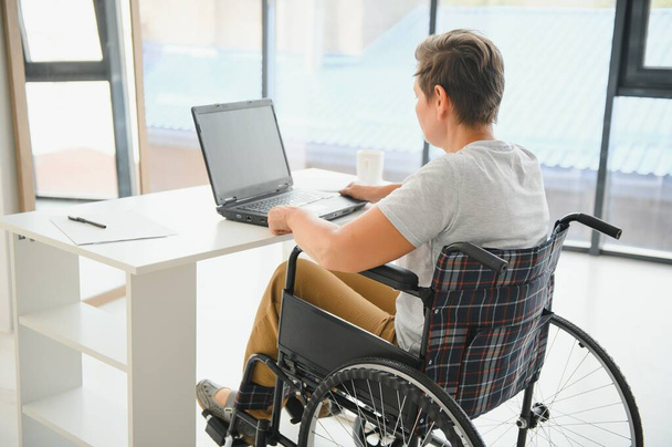 Positive elderly woman in wheelchair working on laptop, IT freelancer, online. - Fotoğraf, Görsel