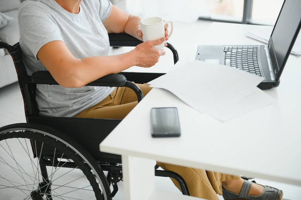 Middle age woman using laptop sitting on wheelchair at home. - Foto, Bild