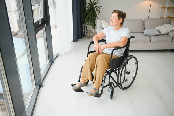 senior woman in wheelchair at home in living room - Foto, afbeelding