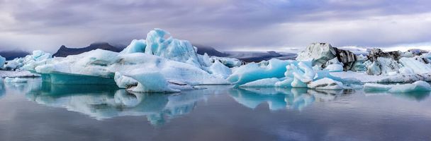 Amplio panorama de la laguna glaciar Jokulsarlon, al sur de Islandia. Reflejo espejo de los icebergs de hielo azul. Parque Nacional Vatnajokull. - Foto, Imagen