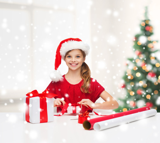 smiling girl in santa helper hat with gift box - Foto, afbeelding