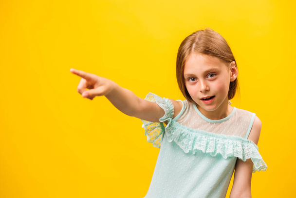 Wow look, advertise here Portrait of amazed cute kid girl pointing to empty place on yellow background, kid warning and childhood concept, copy space - Fotografie, Obrázek