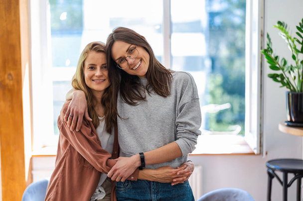 Portrait of affectionate lesbian couple embracing at home - 写真・画像