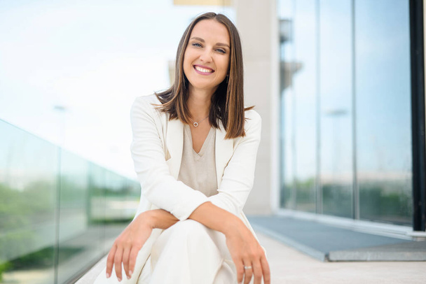 Cheerful young businesswoman in smart casual wear outdoors. Portrait of positive female employee taking a break from office work. - Foto, afbeelding