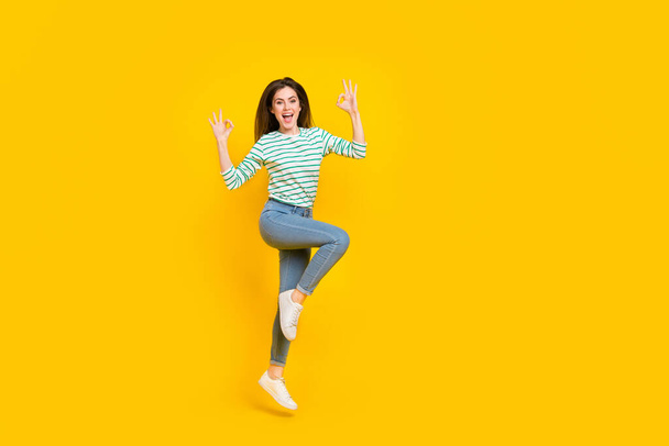 Full size photo of good mood overjoyed girl jumping showing okay symbol isolated on yellow color background. - Foto, afbeelding