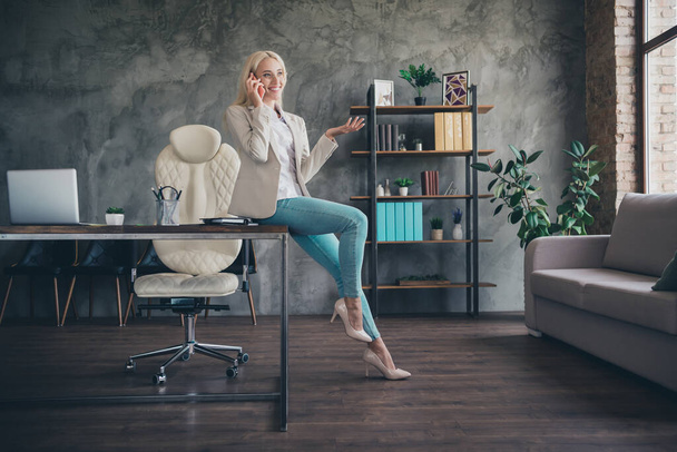 Photo of good mood businesswoman wear blazer sitting table talking modern device indoors workplace workstation. - Zdjęcie, obraz