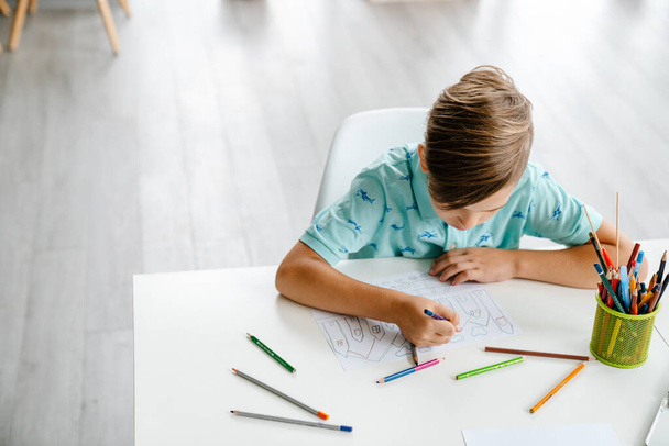 White blond boy drawing during class in art school indoors - Foto, imagen