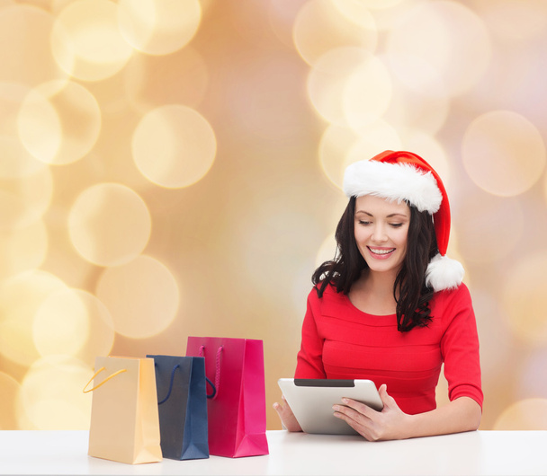 smiling woman in santa hat with bags and tablet pc - Фото, зображення