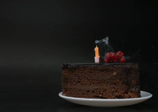 Bir parça çikolatalı pasta, siyah arka planda beyaz tabakta sönmüş bir mum. Doğum günü partisi, kutlama, yıldönümü. Yakın çekim, metin için alanı kopyala. Yüksek kalite fotoğraf - Fotoğraf, Görsel