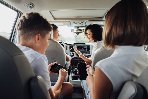 Щасливі чотири члени сім "ї подорожують мінівенською машиною, мати і батько з двома підлітками на дорогах у вихідні - Фото, зображення