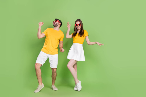 Full body photo of two overjoyed carefree people have fun dancing clubbing isolated on green color background. - Foto, immagini