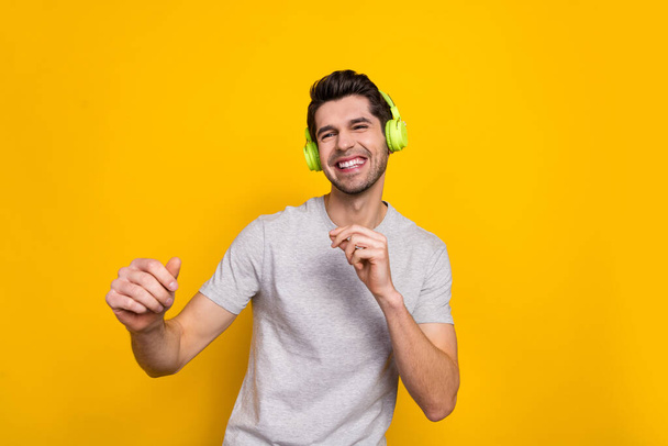Portrait of attractive cheerful guy listening pop hit single dancing chill out isolated over bright yellow color background. - Фото, изображение