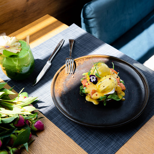 блюдо из красной рыбы и сыра в черной тарелке на деревянном столе в ресторане - Фото, изображение