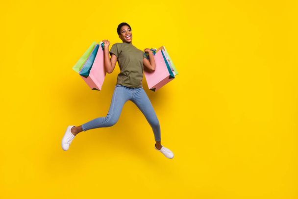 Full length portrait of crazy excited person jump hold packages isolated on yellow color background. - Foto, Bild