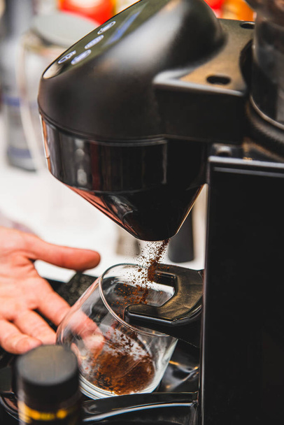 Свіжа мелена кава потрапляє в склянку з м'ясорубки. Створення процесу еспресо
 - Фото, зображення