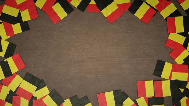 木製のテーブルの上に並べられたベルギーの紙の旗で作られたフレーム。国民のお祝いの概念。3Dイラスト - 写真・画像