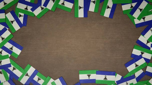 木製のテーブルの上に配置されたレソトの紙の旗で作られたフレーム。国民のお祝いの概念。3Dイラスト - 写真・画像