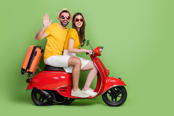 Full body profile photo of handsome guy attractive lady drive bike arm palm waving isolated on green color background. - 写真・画像