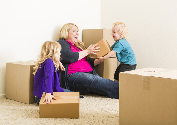 Νεαρή οικογένεια στο άδειο δωμάτιο παίζοντας με τα κινούμενα κιβώτια - Φωτογραφία, εικόνα