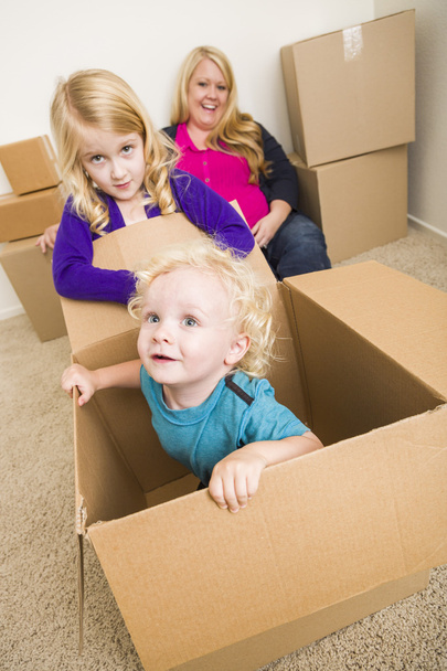 Nuori perhe tyhjässä huoneessa leikkii liikkuvilla laatikoilla
 - Valokuva, kuva