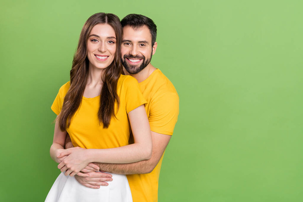 Photo of two cheerful nice partners embrace toothy smile empty space isolated on green color background. - Foto, Bild