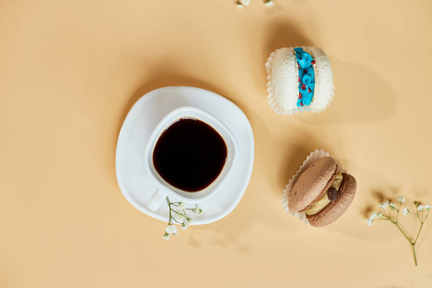 Draufsicht, flache Tortenmacaron, French Cookies Makronen und Tasse Kaffee auf orangefarbenem Hintergrund, bunte Mandelkekse, Pastellfarben, kreative und modische Kompositio - Foto, Bild