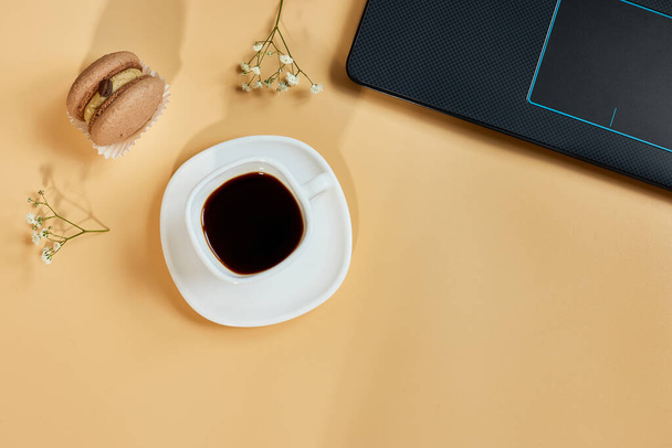 Flat lay, top view office table desk, workspace with laptop, macaroon with coffee cup and flowers, on orange background, working from home, distant work - Φωτογραφία, εικόνα