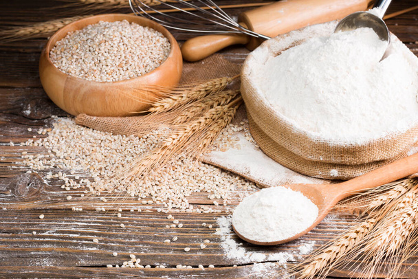 Organic Natural Whole Grain Flour in a Wooden Spoon and wheat seeds Ears of wheat on an old wooden floor - Φωτογραφία, εικόνα