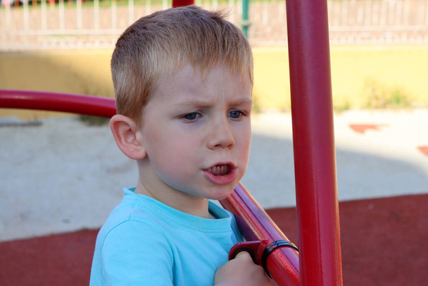 A szőke fiú ráncolta a szemöldökét és duzzogta az ajkait. Felháborodott ötéves fiú. - Fotó, kép