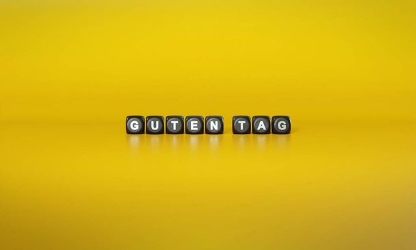 Немецкие слова Guten tag написаны белым текстом на темных деревянных блоках на обычном желтом фоне - Фото, изображение