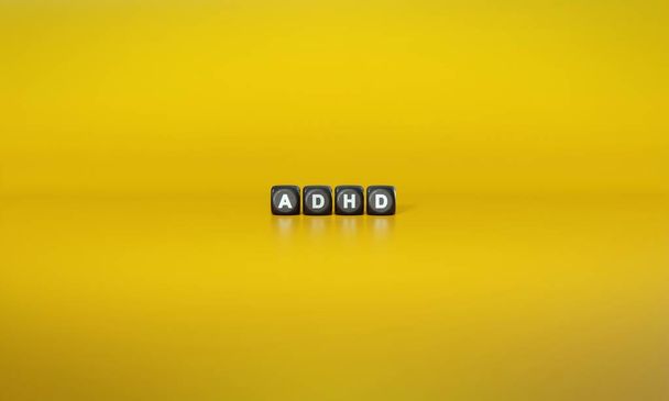 Акроним СДВГ или синдром дефицита внимания Гиперактивность прописан в белом тексте на темных деревянных блоках на обычном желтом фоне - Фото, изображение