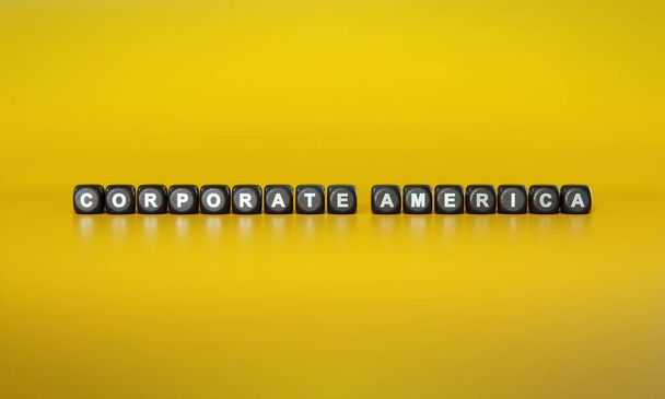 Корпоративная Америка написана белым текстом на темных деревянных блоках на обычном желтом фоне - Фото, изображение
