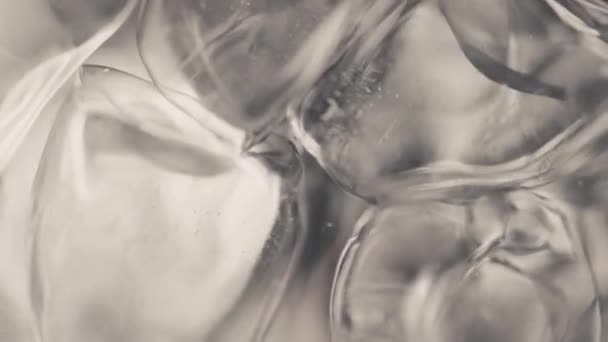 Closeup ice cubes water spinning in slow motion. Aqua waves covered big frozen blocks moving circled in cold beverage. Macro cocktail liquid top view. Refreshing cool summer beverage concept - Footage, Video