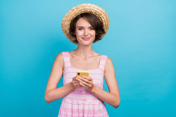 Photo of pretty millennial tourist lady look telephone wear panama pink dress isolated on blue color background. - Фото, изображение